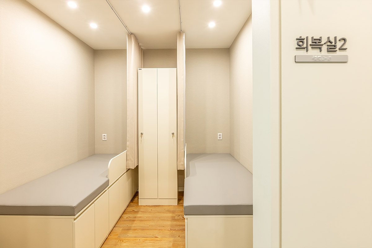 대전사랑니치과 회복실 — 누울 수 있는 침상 두 개를 칸막이로 나눈 회복실과 가운데 수납장